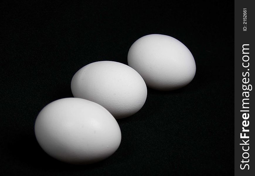 Three large white eggs on black. Three large white eggs on black