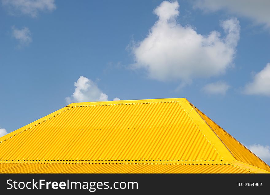 A yellow tile roof against a blue sky. A yellow tile roof against a blue sky