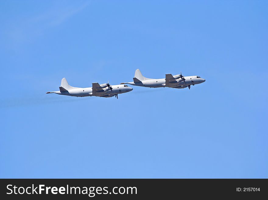 A pair of large military airplanes while on flight. A pair of large military airplanes while on flight