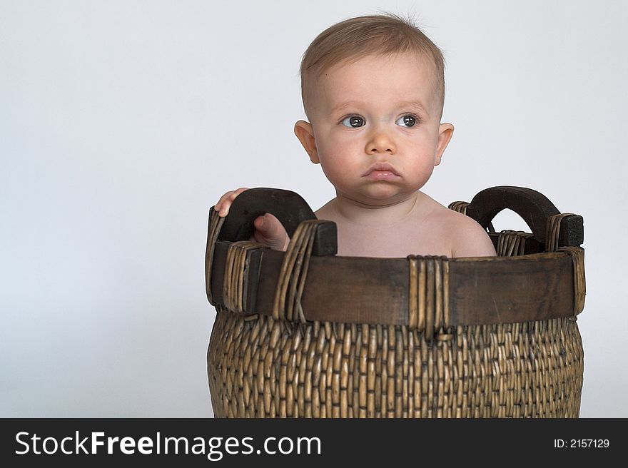 Image of cute baby sitting in a woven basket in front of a white background. Image of cute baby sitting in a woven basket in front of a white background