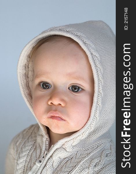 Image of cute baby wearing a hooded sweater, sitting in front of a white background. Image of cute baby wearing a hooded sweater, sitting in front of a white background