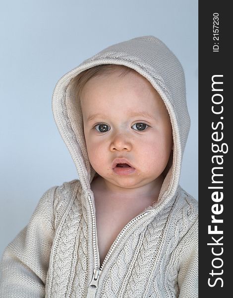 Image of cute baby wearing a hooded sweater, sitting in front of a white background. Image of cute baby wearing a hooded sweater, sitting in front of a white background