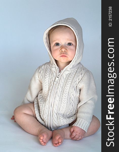 Image of cute baby wearing a hooded sweater, sitting in front of a white background. Image of cute baby wearing a hooded sweater, sitting in front of a white background