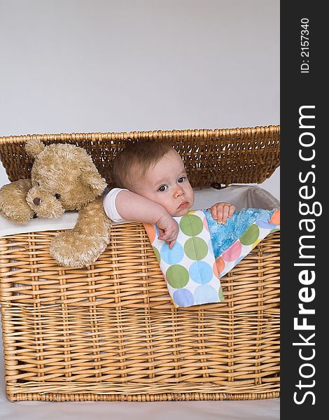 Image of cute baby and teddy bear peeking out of a wicker trunk