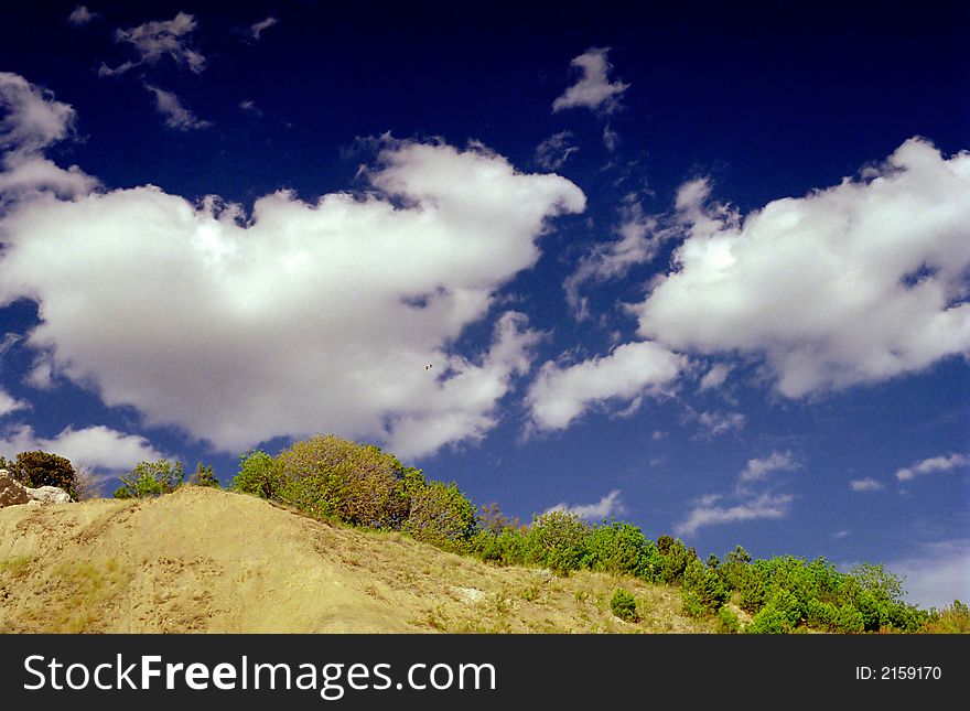 Dark blue clouds above breakage covered with greens. Dark blue clouds above breakage covered with greens