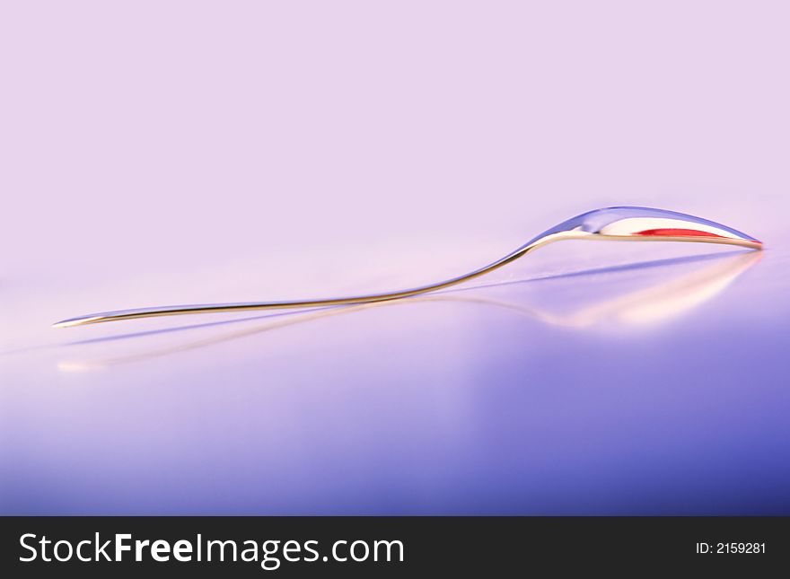 Dessert brilliant spoon on  glass surface and  blue background. Dessert brilliant spoon on  glass surface and  blue background