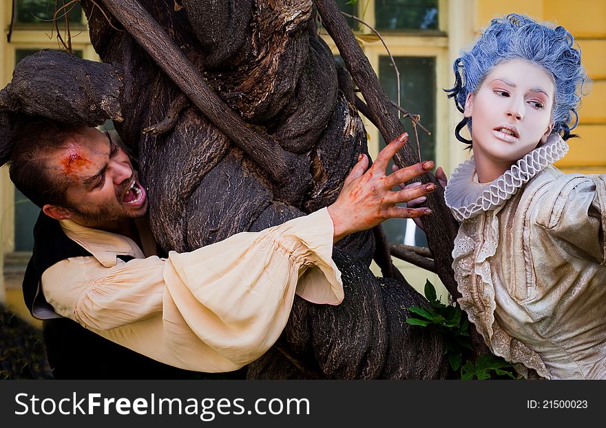 Couple in medieval costumes - male vampire reching hand to women with blue wig. Couple in medieval costumes - male vampire reching hand to women with blue wig