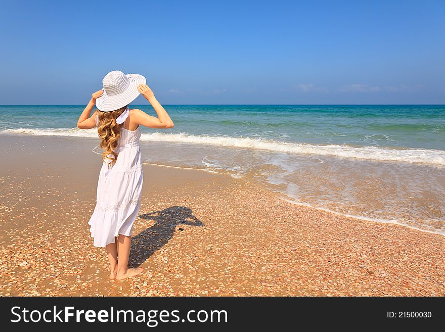 Girl in white dress and white hat standing on the beach. Girl in white dress and white hat standing on the beach