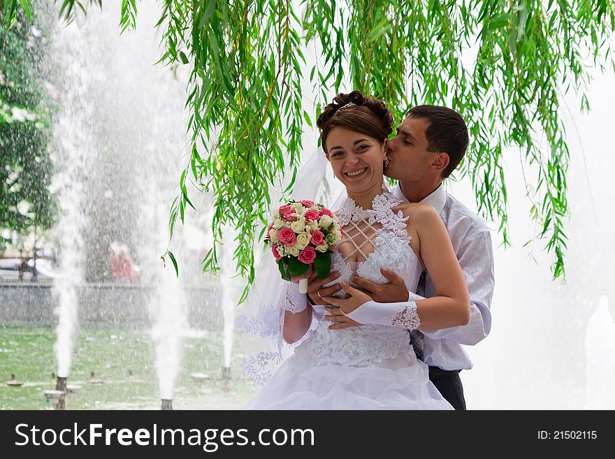 Happy bride and groom standing under the willow