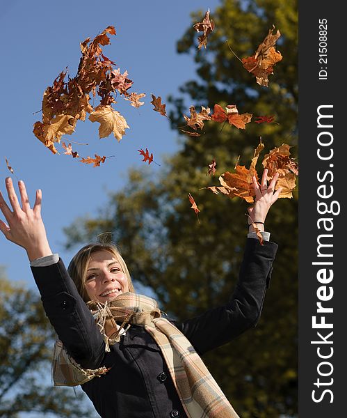 Young beautiful woman throwing the yellow leafs in the air. Young beautiful woman throwing the yellow leafs in the air