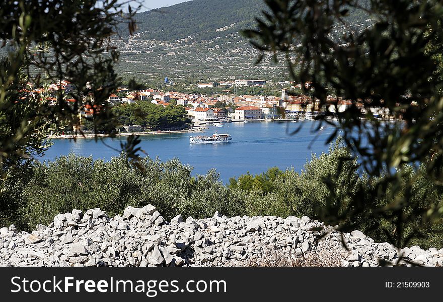 Mediterranean touristic place near sea and ship with look through olive trees