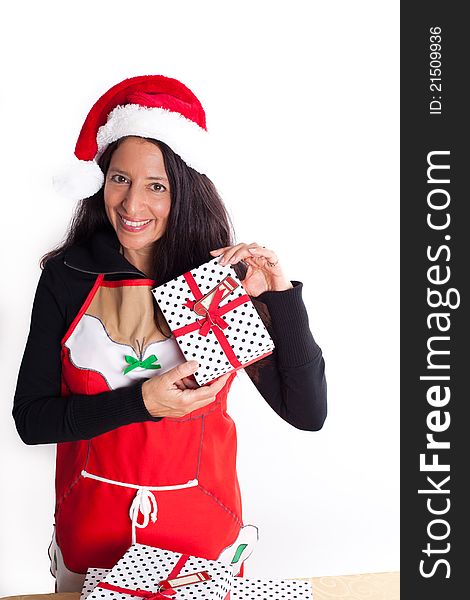 Pretty happy woman wearing a Santa Hat and Santa Apron holding a gift excited about the Holidays. Pretty happy woman wearing a Santa Hat and Santa Apron holding a gift excited about the Holidays