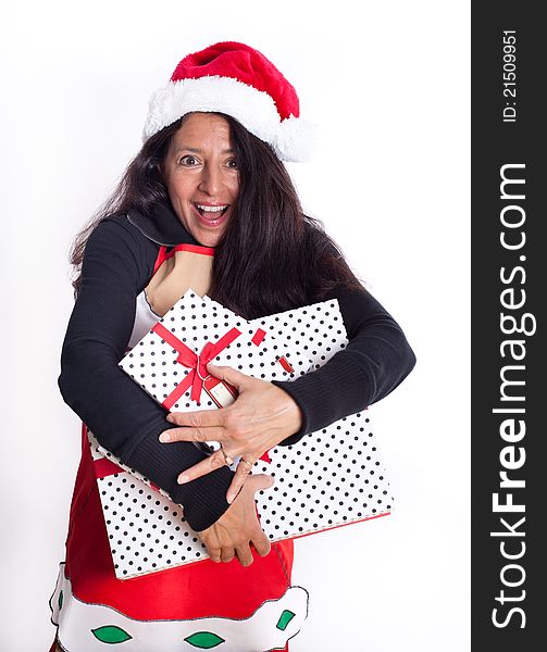 Pretty happy woman wearing a Santa Hat and Santa Apron holding a gift excited about the Holidays. Pretty happy woman wearing a Santa Hat and Santa Apron holding a gift excited about the Holidays