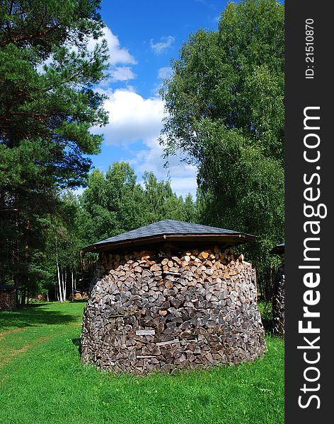 Pile of chopped firewood on the green grass with blue sky. Pile of chopped firewood on the green grass with blue sky