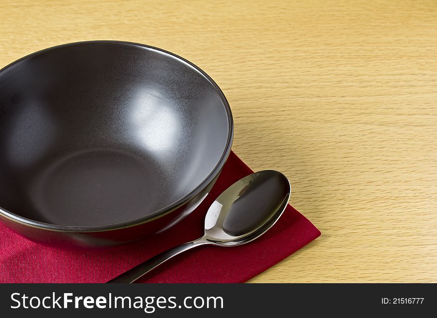 Black bowl with spoon on table with red napkin