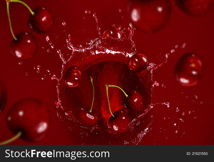 Cherry falling into the juice with huge splashes. Cherry falling into the juice with huge splashes