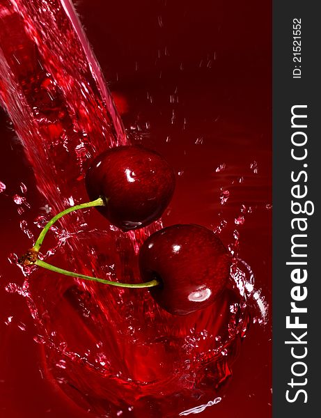 Cherry falling into the juice with huge splashes. Cherry falling into the juice with huge splashes