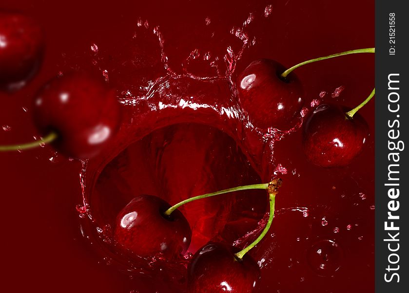 Cherry falling into the juice with huge splashes. Cherry falling into the juice with huge splashes