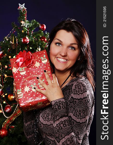 Happy and smiling woman with Christmas gift in hands. Happy and smiling woman with Christmas gift in hands