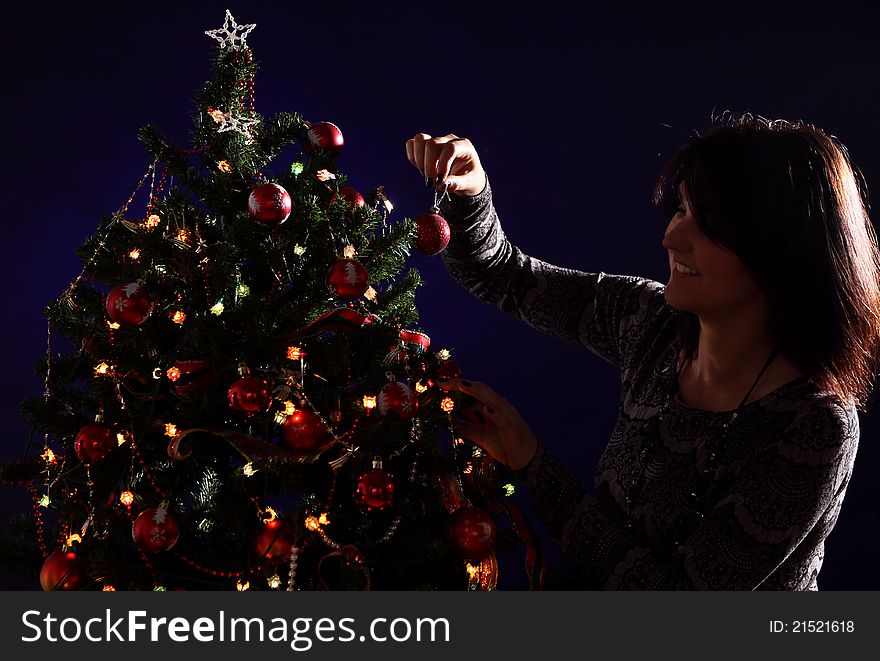 Happy woman are decorating the Christmas tree with different balls