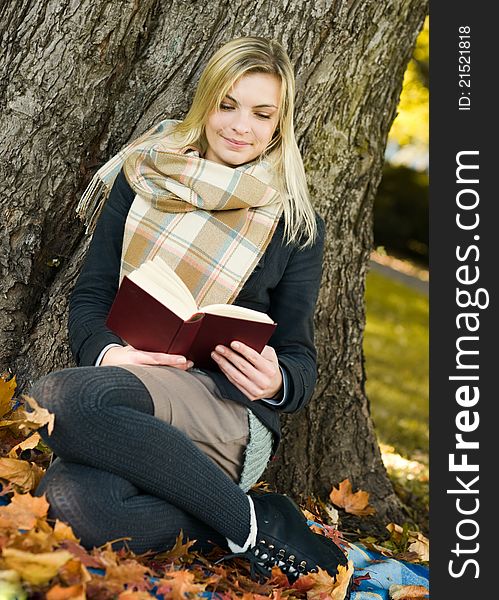 Young beautiful woman reading the book in at autumn park. Young beautiful woman reading the book in at autumn park