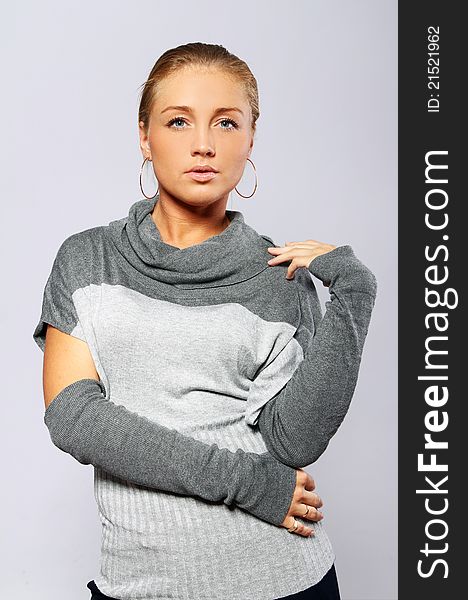 Beautiful woman in pullover posing over gray background. Beautiful woman in pullover posing over gray background