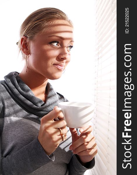 Beautiful woman with cup of coffee beside a window