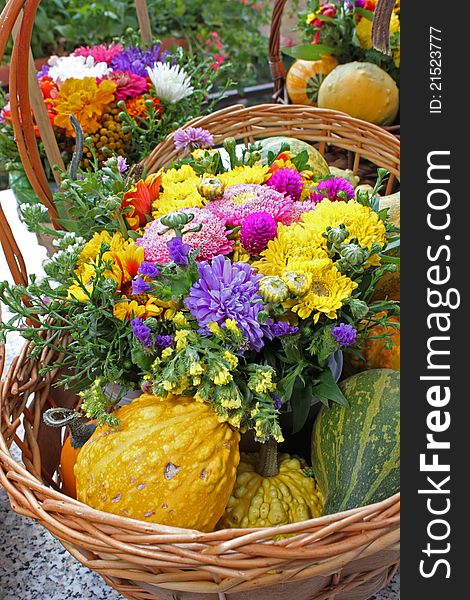 Assorted flower and pumpkin basket on outdoor grey table. Assorted flower and pumpkin basket on outdoor grey table.