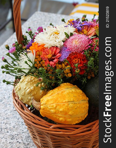 Assorted flower and pumpkin basket on outdoor grey table. Assorted flower and pumpkin basket on outdoor grey table.