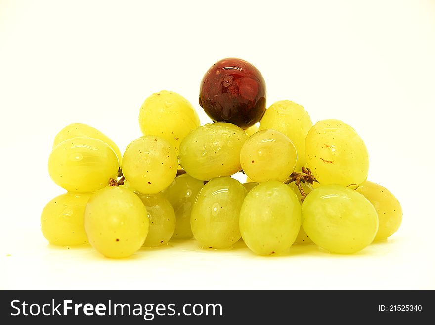 Image of a cluster of green grapes with a black grape.