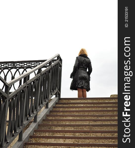 Blond, stone steps, iron castings, the woman standing at the top, place for a slogan, lettering or logo. Blond, stone steps, iron castings, the woman standing at the top, place for a slogan, lettering or logo