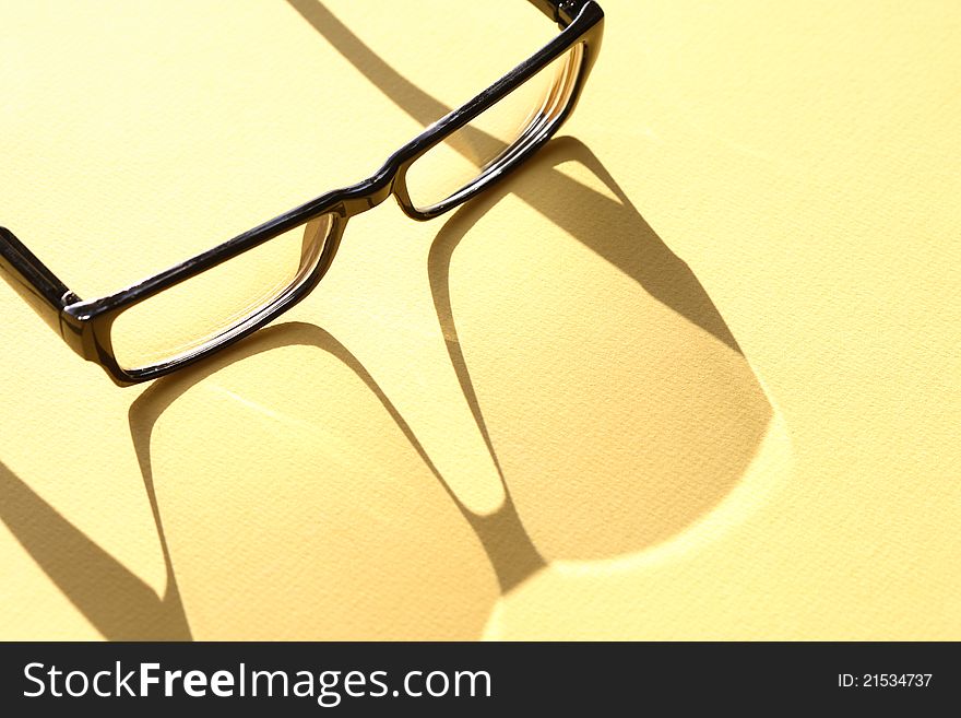 Closeup of spectacles with long shadow on yellow surface. Closeup of spectacles with long shadow on yellow surface