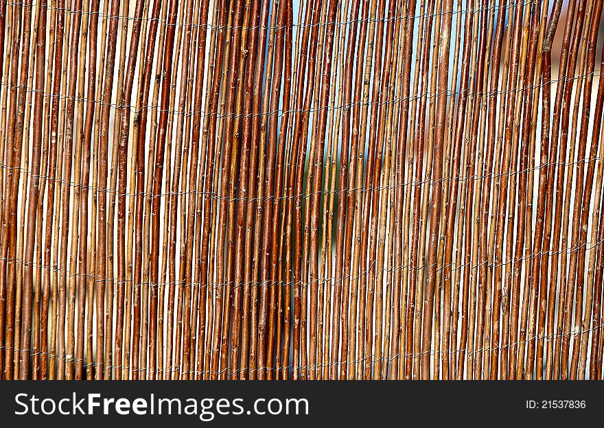 Vertical wooden willow fencing with strands of metal wire holding it together. Vertical wooden willow fencing with strands of metal wire holding it together.