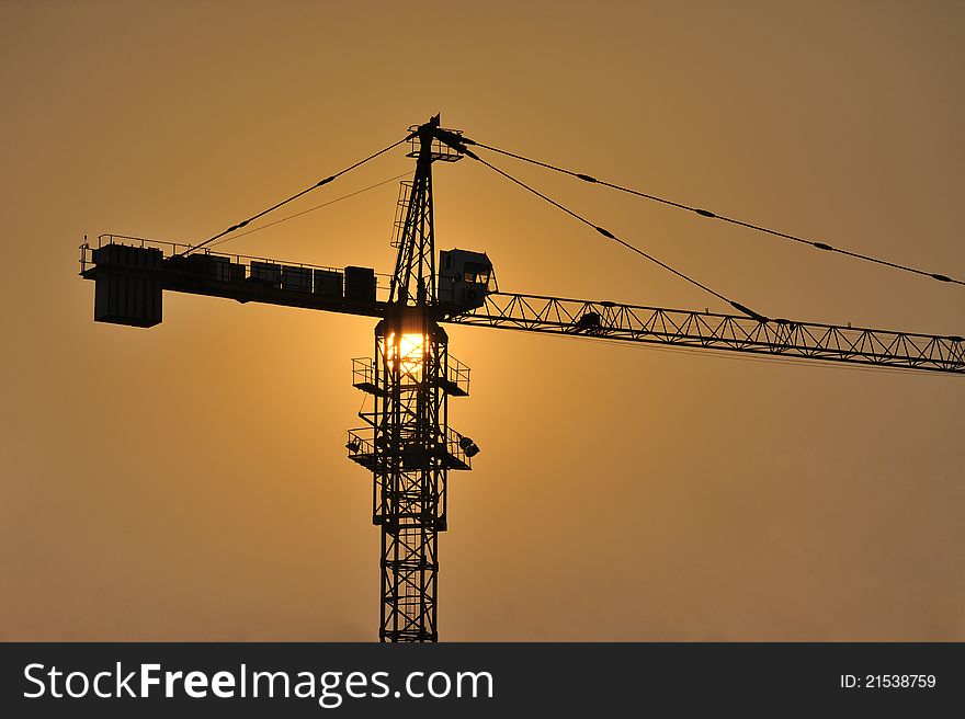 Three cranes at a construction site during sunset. Three cranes at a construction site during sunset.