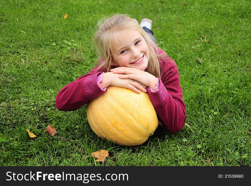 Little girl laying on green grass with pumpkin. Little girl laying on green grass with pumpkin