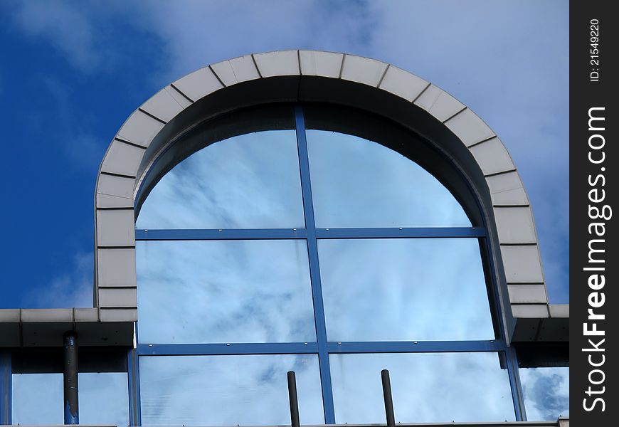 Arched window at entrance to shopping center in Bodo, Norway.  Clouds are reflected in the windows.