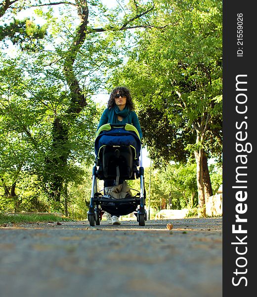 Mother walking with her child in nature, pushing children carts in the park on nice weather in stroller. Mother walking with her child in nature, pushing children carts in the park on nice weather in stroller
