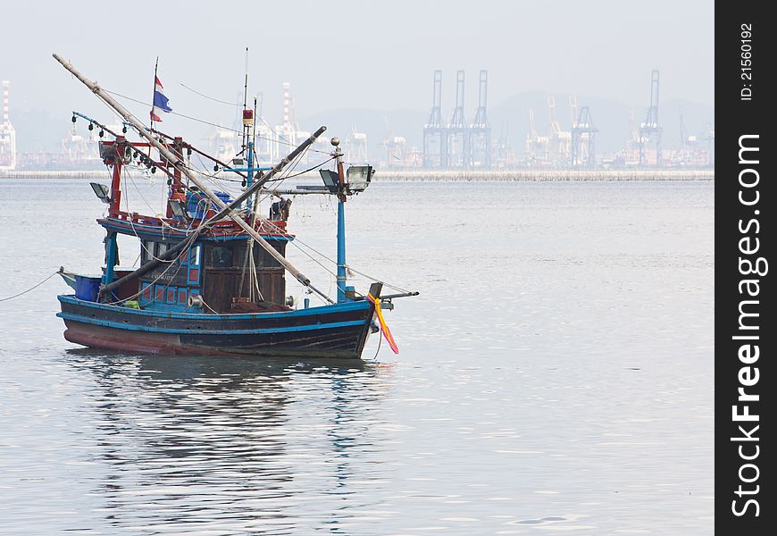 Fishing boat in the sea on industrial background