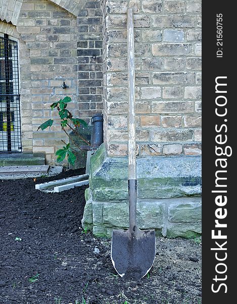 Spade leaning against stone wall in garden. Spade leaning against stone wall in garden