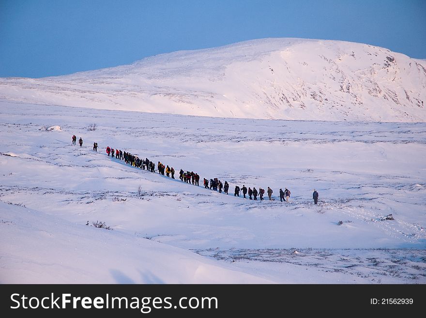 People are walking in row on snow in Norway. People are walking in row on snow in Norway