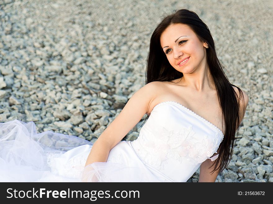 Portrait of a beautiful bride on pebbles outdoor