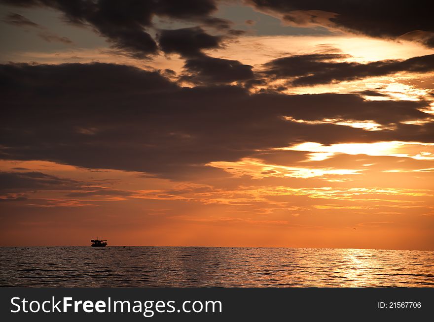 Dramatic Orange Sunset With Clouds And Boat On Sea