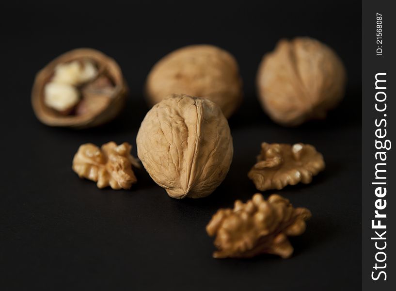 Cracked and whole walnuts in black background