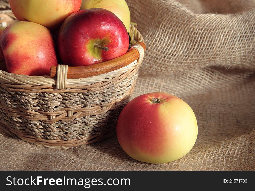 Apples in a basket and one apple lies nearby. Apples in a basket and one apple lies nearby.