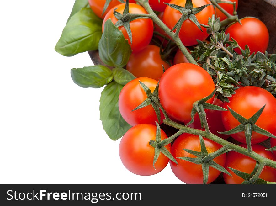 Cherry tomatoes with basil and thyme in wood plate isolated on white