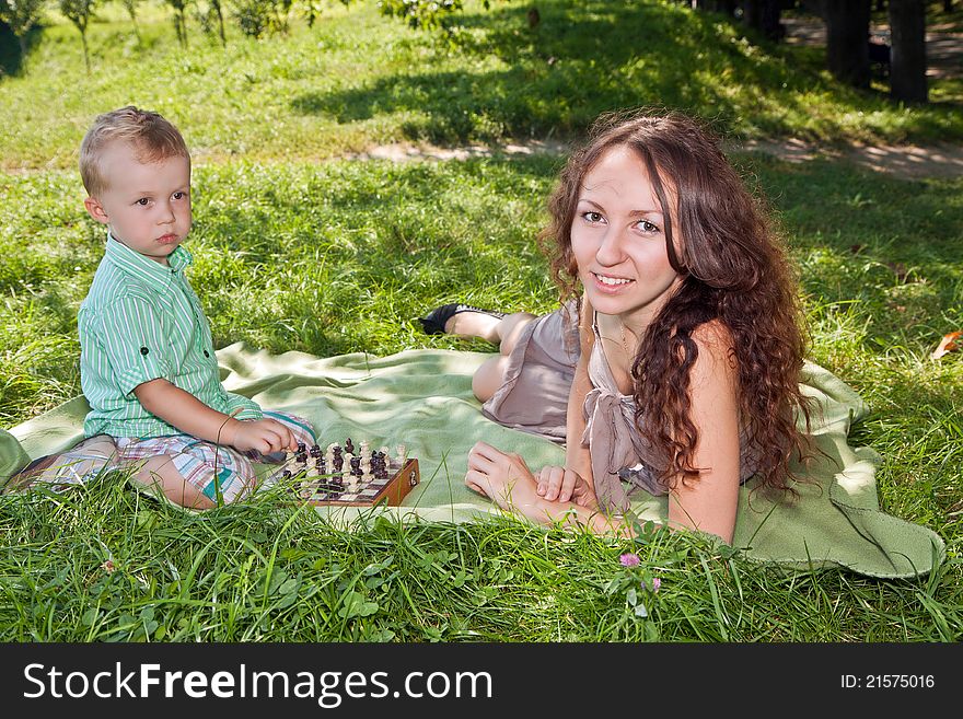Mother teaches her son to play chess in the park. Mother teaches her son to play chess in the park