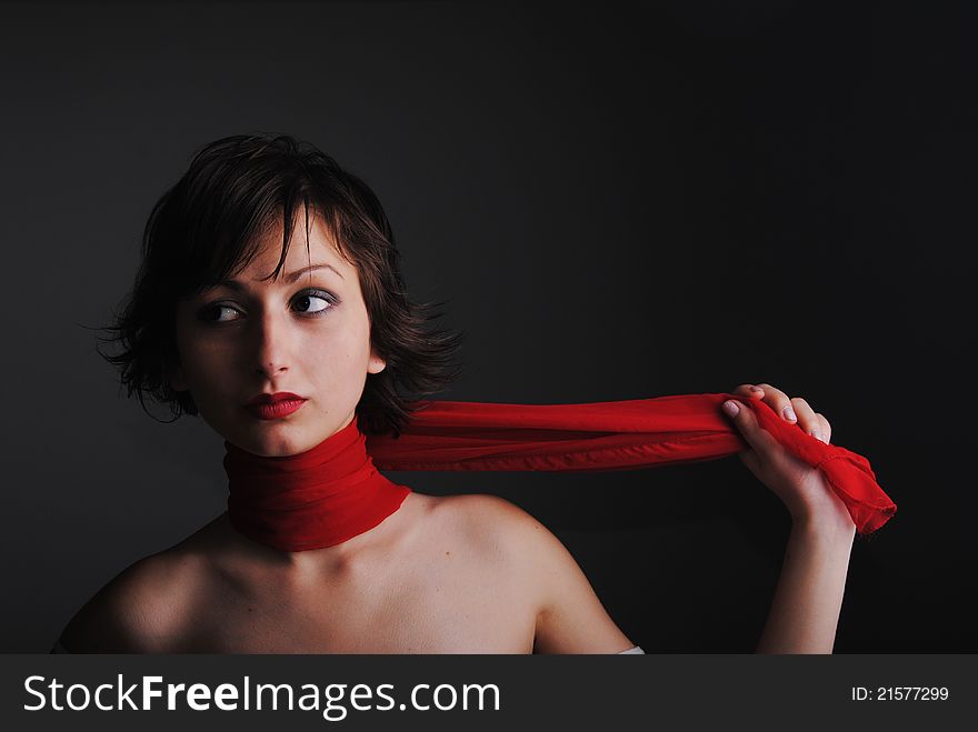 Portrait of girl in red a scarf on a grey background.