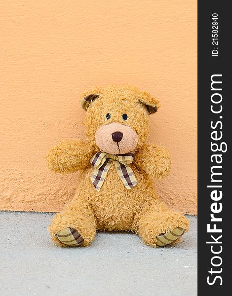 Teddy Bear with plaid bow on wall orange background