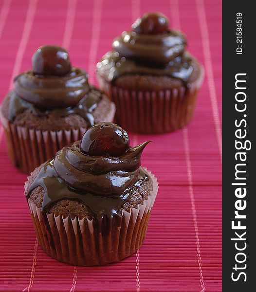 Delicious chocolate cup cakes with dark chocolate cream and cherries