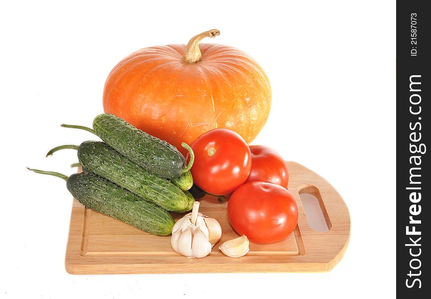 Cucumbers, tomatoes on a board and a pumpkin lie on a table. Cucumbers, tomatoes on a board and a pumpkin lie on a table